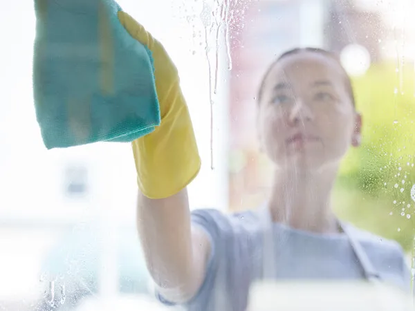 A lady cleaning her window with a cloth